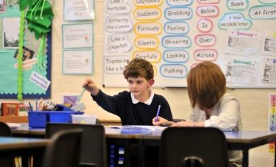 Teacher recording observations of student working.